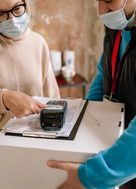 Delivery worker using a digital payment terminal while handling a shipment