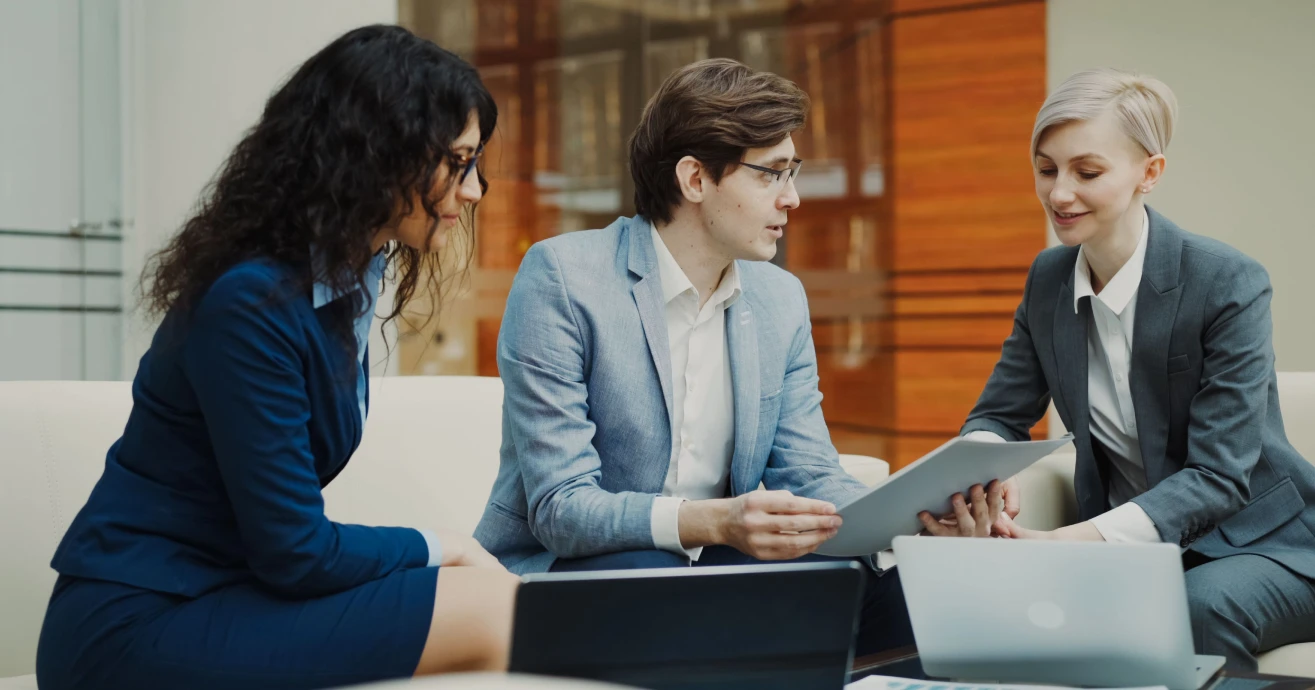 Professionals discussing a project with a tablet and laptops