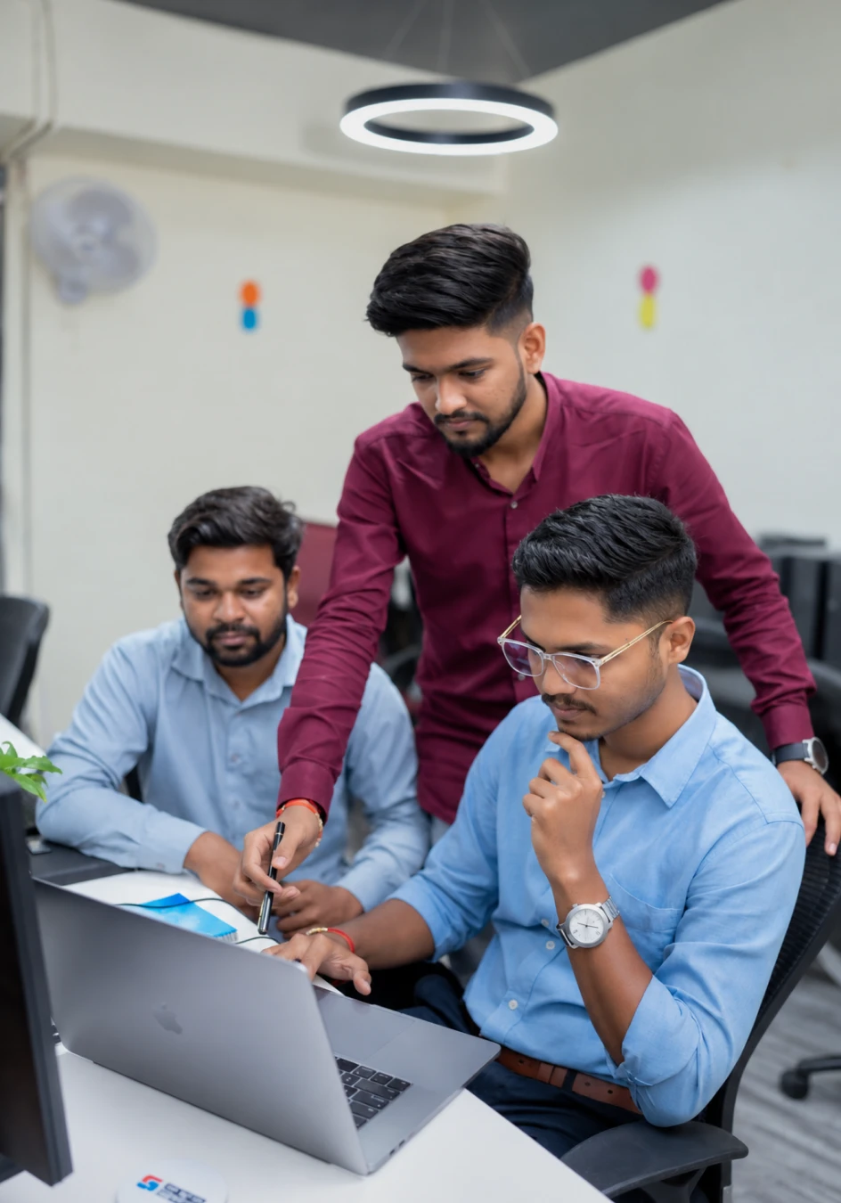 Team members collaborating on a project around a laptop